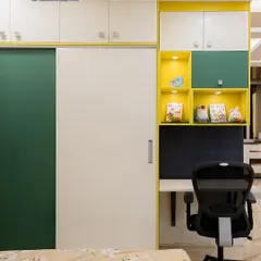 This vibrant kids' room features a wardrobe with an attached study nook. The bright yellow and green color scheme, along with open shelves for books and toys, creates a cheerful and organized space.