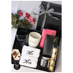 A classic 'Hubby & Wifey' hamper. This gift set includes matching mugs, 'Mr. & Mrs.' hand towels, personalized passport wallets, and a 'Love Story' candle.