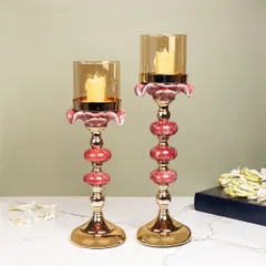 These elegant candle stands feature a beautiful combination of pink ceramic orbs and gold metal. The glass hurricane shade protects the flame while adding to the sophisticated design.