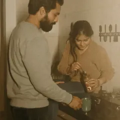 A simple, domestic scene filled with love. The couple makes coffee together in their kitchen, a quiet morning ritual that speaks to the comfort and partnership in their relationship.