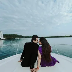 An intimate moment on the bow of a yacht, with the water and shoreline in the background. This shot captures the feeling of a private, luxurious escape.