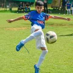 Here, we focus on mastering the fundamentals. This young player demonstrates excellent ball control and kicking technique, skills we build in every session.