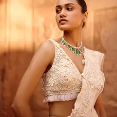 A close-up of the delicate floral embroidery on this ivory blouse from the Awigna campaign shoot. The emerald necklace adds a perfect pop of color.
