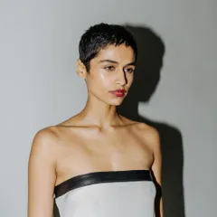 A quiet portrait of a model backstage. The direct, hard light creates a strong shadow, adding a graphic quality to this behind-the-scenes shot.