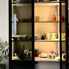 The fully stocked crockery unit showcases its generous storage capacity. The combination of glass shelves for delicate items and solid bases for heavier sets makes it a highly practical piece of dining room furniture.