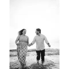 A playful moment in black and white, as the couple runs through the shallow water. The motion and splashes create a dynamic and joyful image that feels full of life.