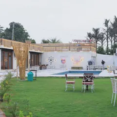 A daytime view of our expansive property, showing the green lawns and the poolside seating area. It's the perfect spot to unwind.