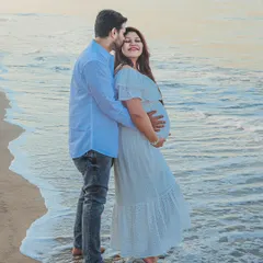 An outdoor maternity photoshoot at the beach, capturing a quiet moment between the expecting couple. The soft evening light and gentle waves create a serene and romantic backdrop for your pregnancy portraits.