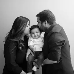 Surrounded by love. This beautiful black and white portrait captures the tender kisses of parents for their happy baby.