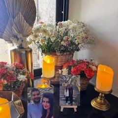 A cozy corner at a home Roka ceremony. We created a memory lane for the couple by displaying their photos on mini easels, surrounded by fresh flowers and the warm glow of candles.