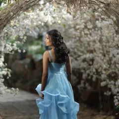 The bride-to-be looking like a princess in her pastel blue gown, walking through the 'Garden of Promises' I designed for her brunch. The archway of white flowers creates a truly ethereal portrait.