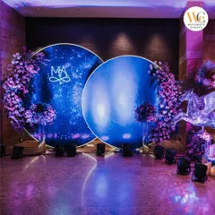 The stage for a celestial-themed Sangeet, featuring two large circular LED screens displaying a galaxy effect, framed by purple flowers and a crystal pegasus.