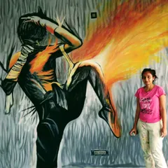Here I am with a finished gym graffiti mural. The fiery, energetic figure was created with spray paint to inspire movement and power. It's about 20 feet wide and 11 feet high.