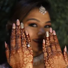 A beautiful bride showcasing her custom wedding nails, designed to complement her intricate henna. This set features a soft pink base with sparkling silver glitter accent nails.