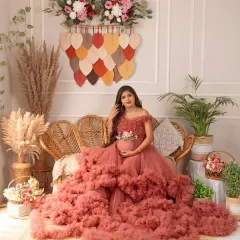 The full view of the boho setup, complete with a cane sofa, pampas grass, and unique wall hangings. This mama-to-be looks absolutely radiant in her ruffled gown.