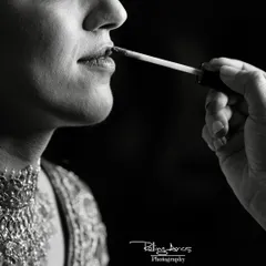 A dramatic black and white close-up of the final touch of lipstick being applied. This artistic shot focuses on the small, intimate details of the bridal preparation process.