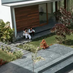 The pool house at Rosewood Farmhouse is nestled within the landscape, creating a perfect spot for outdoor entertaining. Here, two of our designers are seen enjoying the seamless transition from the built structure to the manicured lawn and layered garden beds.