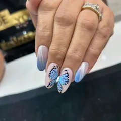 Let your nails take flight with our custom hand-painted butterfly art. This detailed design is set against a beautiful blue ombré and cat eye background, showing the delicate and artistic work our nail technicians are capable of.