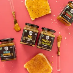 A playful flatlay showing different jams and marmalades on toast. This image demonstrates the product in use, making it relatable and inspiring for customers. The bright pink background is fun and grabs attention.
