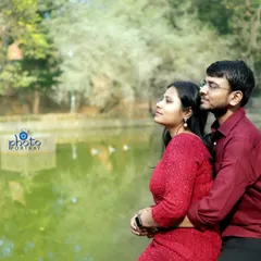 A romantic embrace by the lake, capturing a candid moment as the couple looks out at the view. The natural daylight and green backdrop make for a beautiful outdoor couple photo.