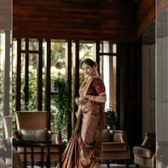 A beautiful bridal portrait in a modern, well-lit hotel lobby, her traditional saree contrasting with the contemporary background.