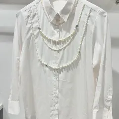 It's all in the details. This classic white shirt is crafted from opulent Swiss cotton and elevated with delicate, hand-draped pearl embellishments, turning a wardrobe staple into a statement piece for lunches or evening events.