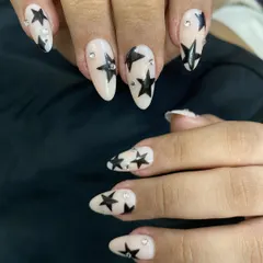 A full view of the star-studded press-on nails on my client's hands. The almond shape of the nails complements the graphic star design perfectly.