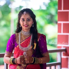This is a perfect example of a modern reception look. The client is wearing a vibrant pink and purple Kanjeevaram saree with elegant diamond jewelry. Her makeup is glamorous yet sophisticated, with soft, flowing curls completing the style.