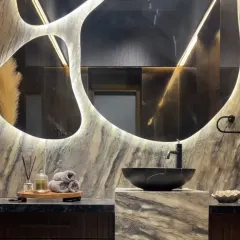 The art of luxury is in the details. In this powder room, a custom-designed, backlit mirror creates a dramatic focal point, complemented by the rich texture of marble and a modern vessel sink. It’s a testament to how thoughtful design can turn a functional space into a personal sanctuary.