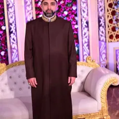 Shaykh Hashim al-Gaylani in a full-length view of his custom Overcoat Sherwani, standing with grace and poise at a formal event.