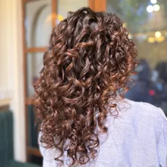 After: A rich mocha balayage adds incredible depth and shine. Notice how the highlights catch the light and make the curls look more dynamic and full of life.