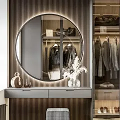 This design showcases a luxurious walk-in closet and dressing area. It features a large backlit circular mirror, a sleek vanity table, and a glass-fronted wardrobe with internal lighting to display clothing and accessories.