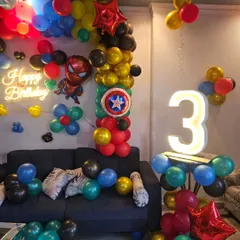 A detailed shot of the superhero birthday setup, focusing on the light-up number, Captain America's shield balloon, and the Spider-Man character.