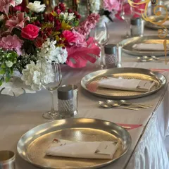 We believe the magic is in the details. This beautifully set tablescape, with its lush floral arrangements and elegant hammered-metal plates, shows our commitment to creating a complete aesthetic experience that complements the menu and your event's theme.
