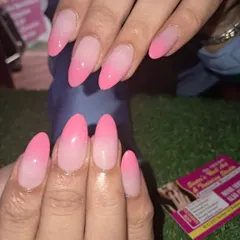 A vibrant pink ombre on long almond-shaped nails. The color fades beautifully from a soft, light pink to a bright, bold pink at the tips.