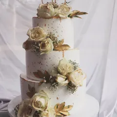 A beautiful and classic three-tier design. The cake is decorated with white roses, baby's breath, and a touch of gold for an elegant and timeless wedding aesthetic.