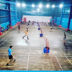 A wide view of our bustling indoor badminton academy during a group training session. Multiple courts are active with players engaged in various drills, showcasing our capacity to train numerous athletes simultaneously.