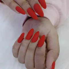 A side view of the long, matte red almond nails, showing their elegant shape.