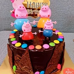 This is a fun chocolate version of the Peppa Pig theme cake. It features a rich chocolate ganache, a chocolate shard border, and colorful gems, along with the adorable Peppa Pig family toppers.