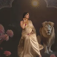 A serene and ethereal portrait that feels like a dream. The mother, draped in a golden-white saree, is depicted with a white lion against a backdrop of lotuses and celestial symbols, creating a fine art piece that speaks of purity and divine motherhood.