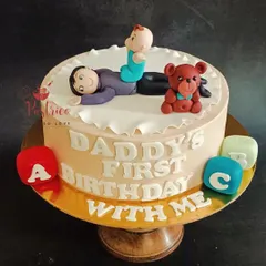 A special cake for a new dad celebrating his first birthday as a father, with a cute topper of him and his baby.