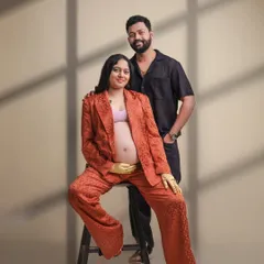 A modern and stylish couple's maternity portrait. The coordinated outfits and relaxed pose showcase a contemporary approach to pregnancy photography in our studio.