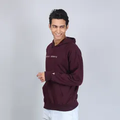 A side profile of a model wearing a maroon "Rise Above" hoodie. This clean, professional shot is ideal for e-commerce catalogs and lookbooks.