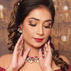 A close-up of this stunning reception look. The focus is on the golden smokey eye, perfectly blended for a glamorous effect, paired with a classic red lip and intricate jewellery.