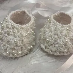 A close-up of my pearl-studded baby shoes, crafted with soft Ganga Desire yarn. The pearls are securely woven in for a beautiful and durable design.