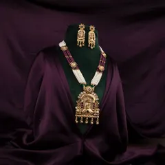A stunning temple jewellery necklace and earring set displayed on a green bust, with draped purple satin creating a sense of luxury and elegance.