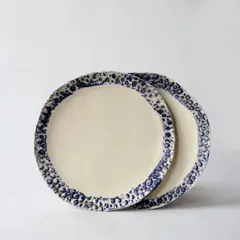 A set of our unique dinner plates featuring a textured, deep blue bubbly glaze around the rim. The contrast with the smooth, cream-colored center makes for a striking design on your dining table.