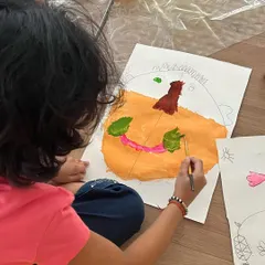 A young artist adding the final touches to her self-portrait. We guide them with basic proportions, but the style, color, and expression are entirely their own.