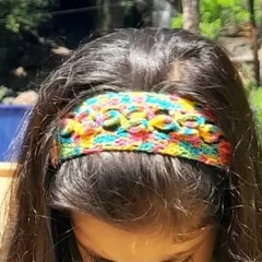 A close-up shot of the multi-color crochet headband, showcasing the detailed floral pattern.