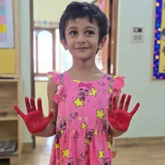 A proud artist with her red-painted hands. These simple art activities help build confidence and allow for creative self-expression.